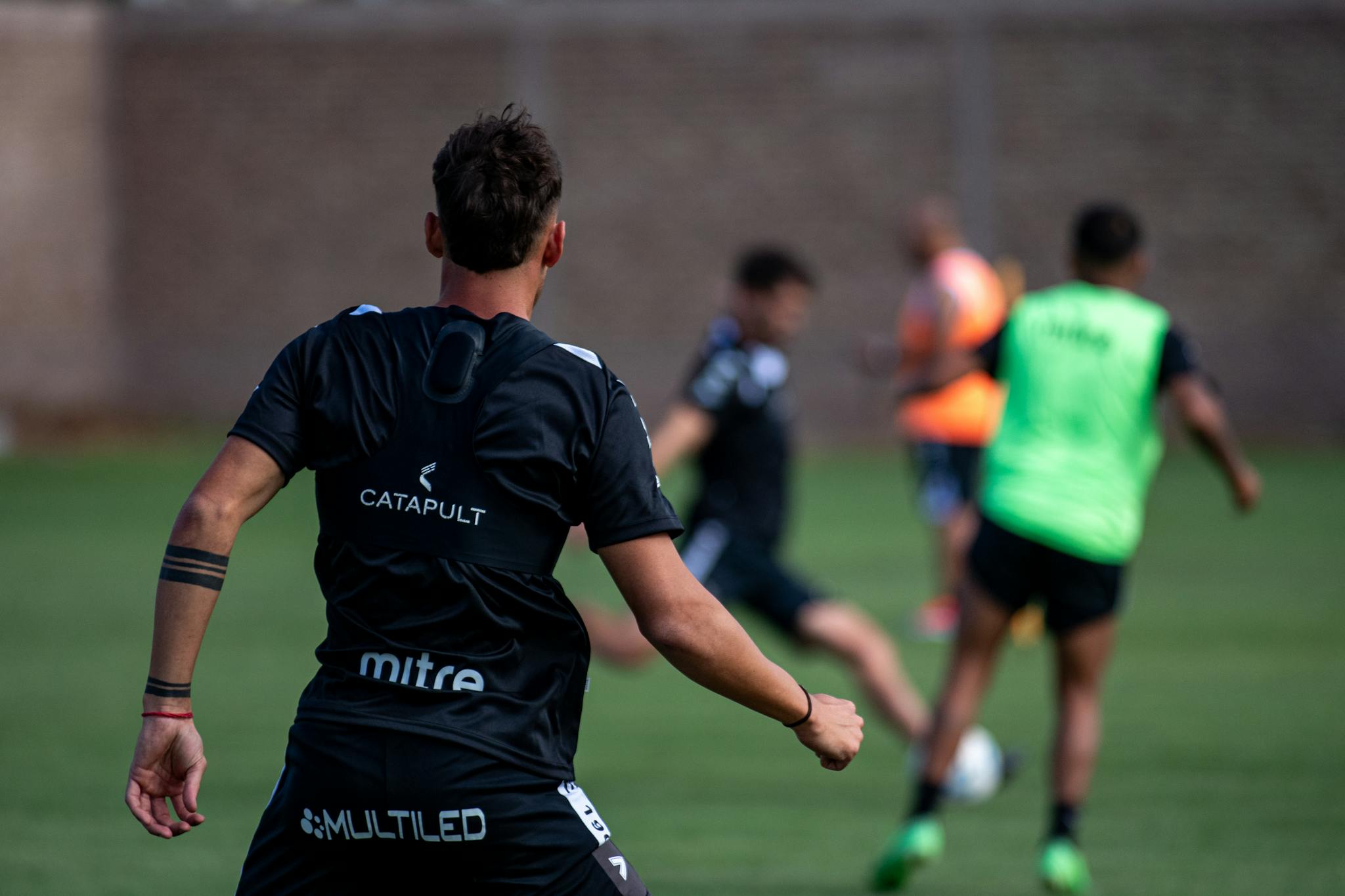 Soccer players practicing on a grassy field in daylight, focused on team exercises.