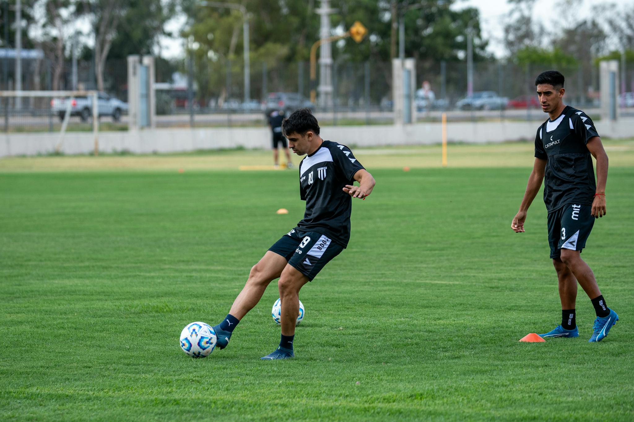 Two soccer players practicing on a green field, focusing on team training.